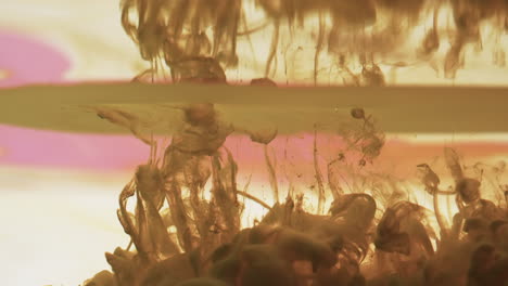 video en cámara lenta de tinta de acuarela marrón mezclándose en agua contra un fondo negro