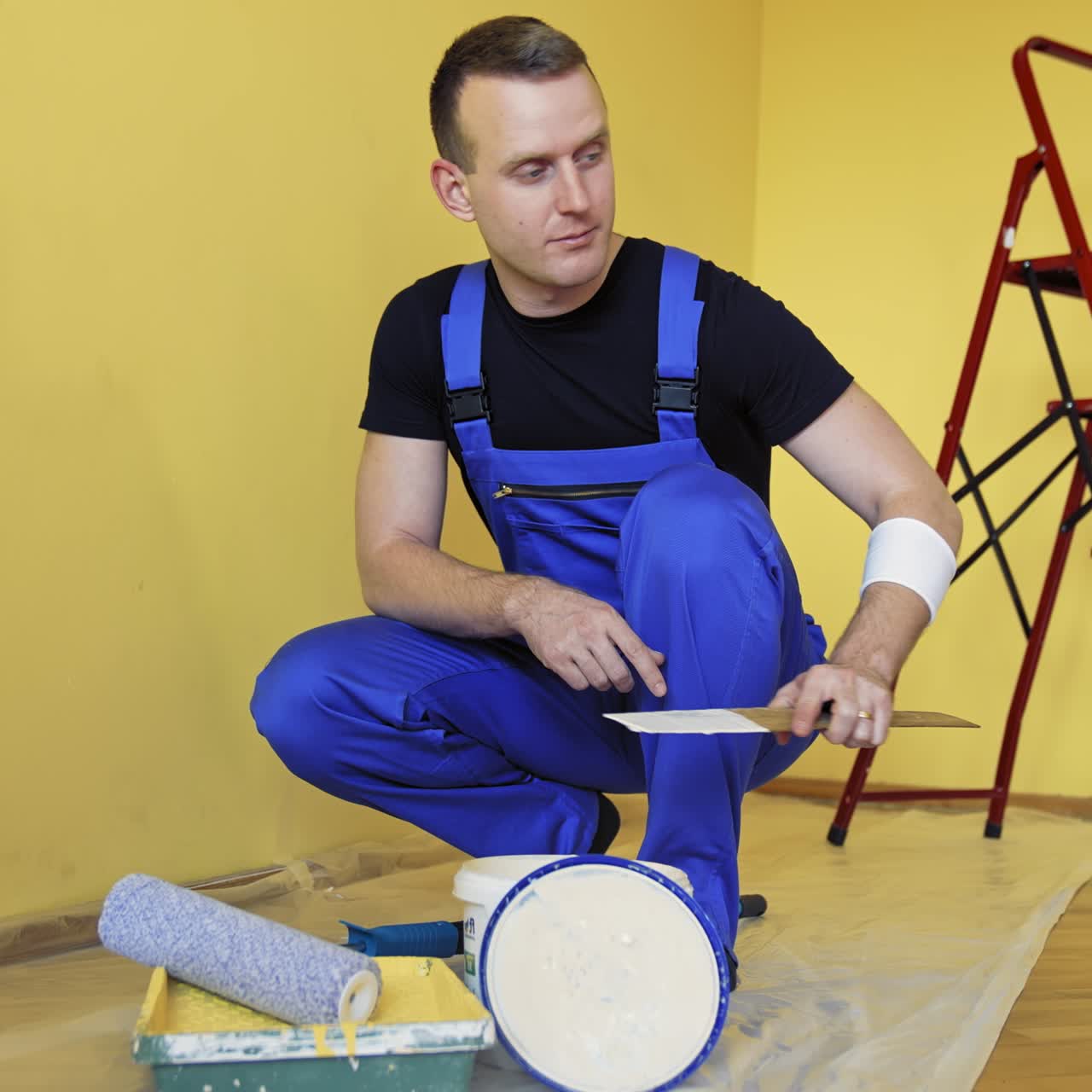 Handsome painting master doing room renovation. Professional painter renovating the room