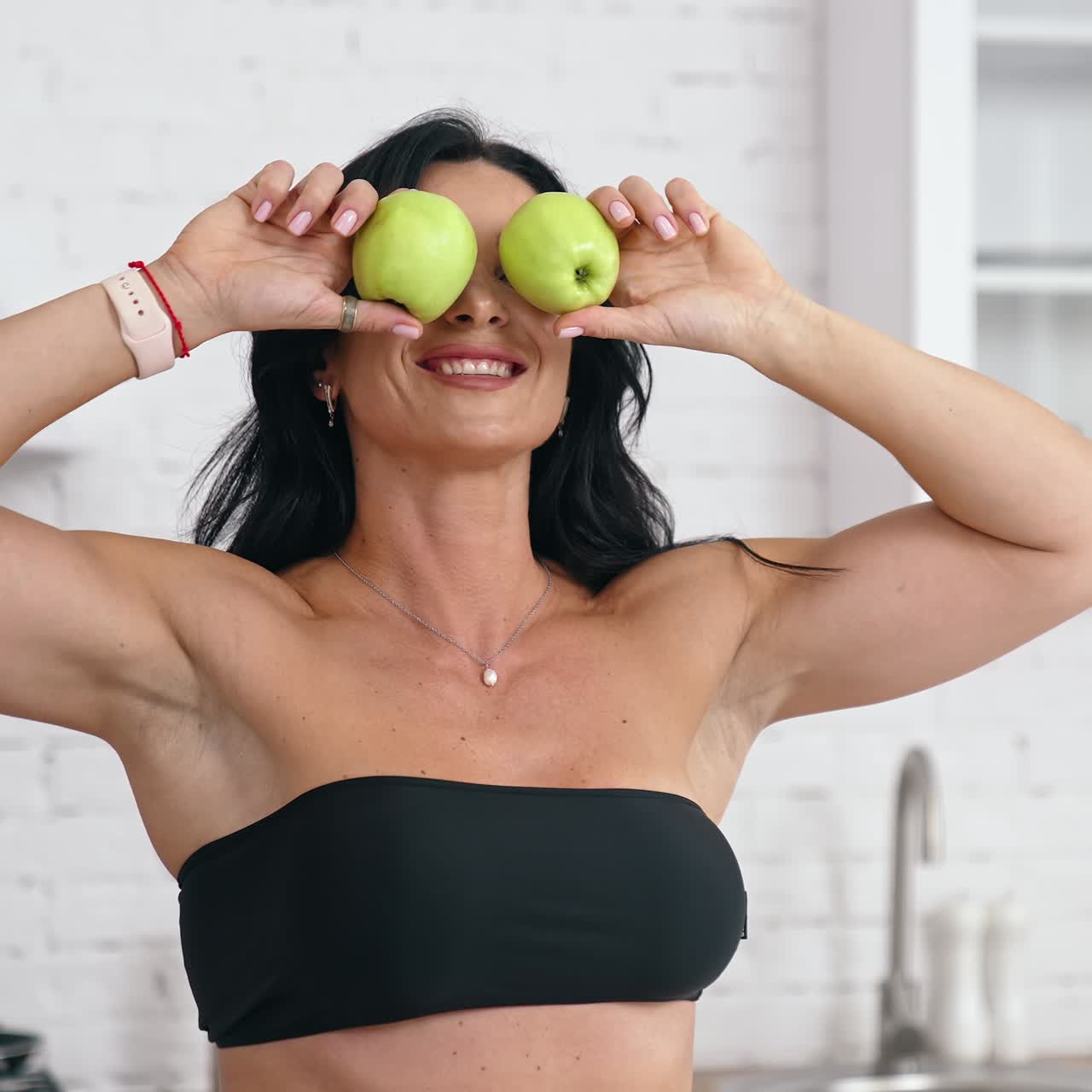Pretty brunette caucasian woman standing near table with healthy apples and playing with it. Healthy diet food concept