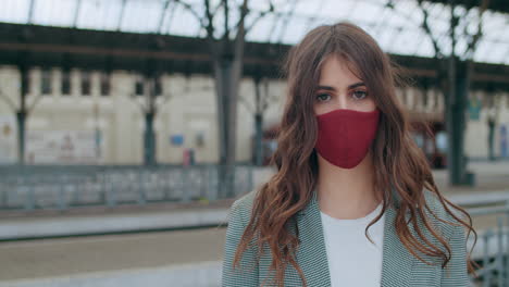 young woman wearing red face mask at a train station