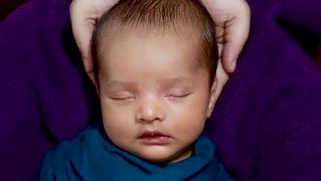 cute-newborn-baby-sleeping-at-mom-palm-in-baby-wrap-from-top-angle-shot