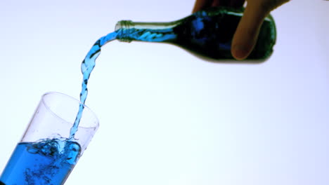 líquido azul que se vierte en el vidrio ángulo bajo
