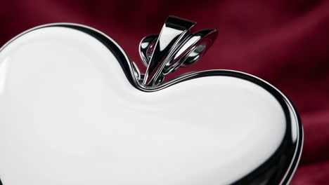 shiny metallic heart-shaped box on red fabric