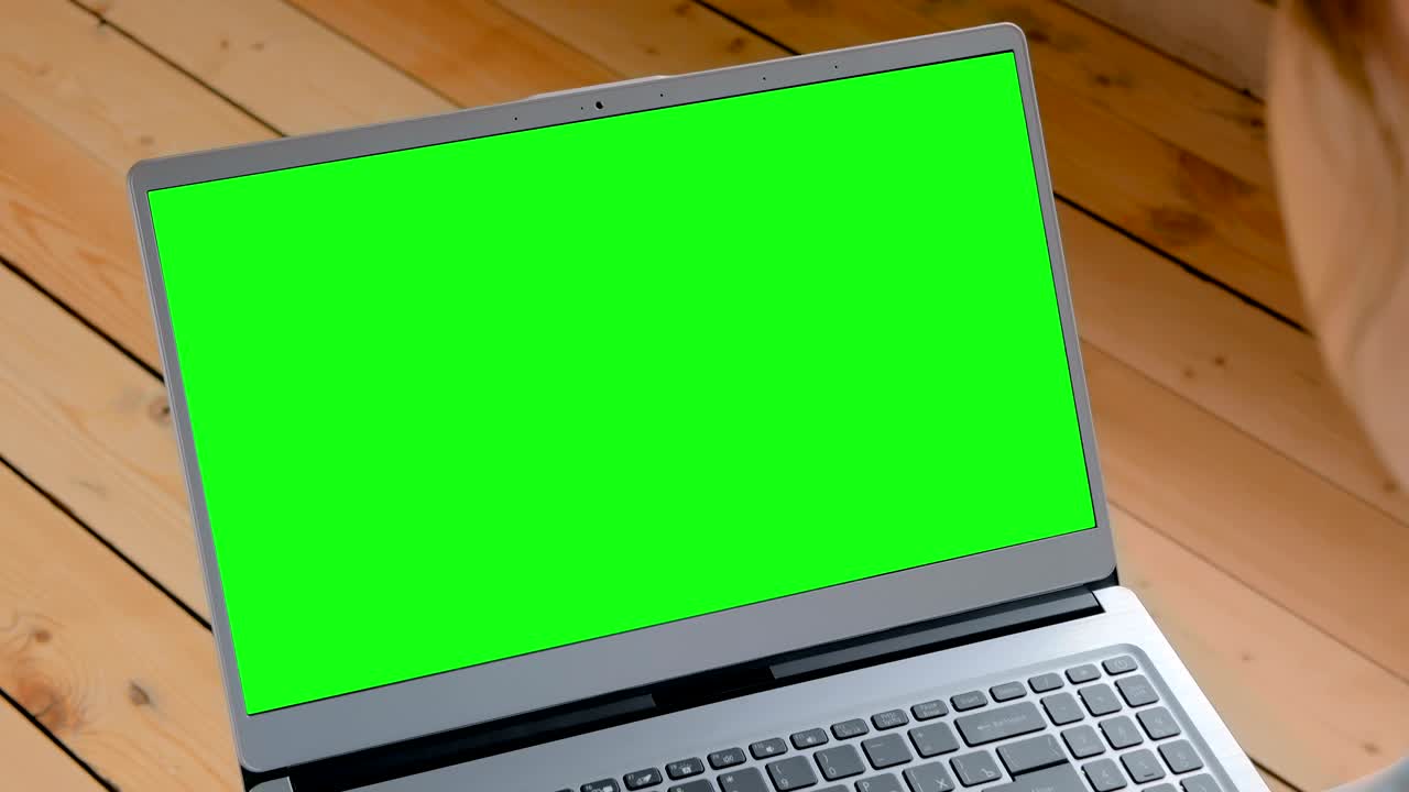 Woman looking at laptop with empty green display