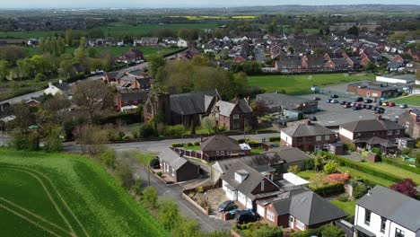 Aerial-view-over-rural-British-countryside-village-surrounded-by-farmland-fields,-Cheshire,-England