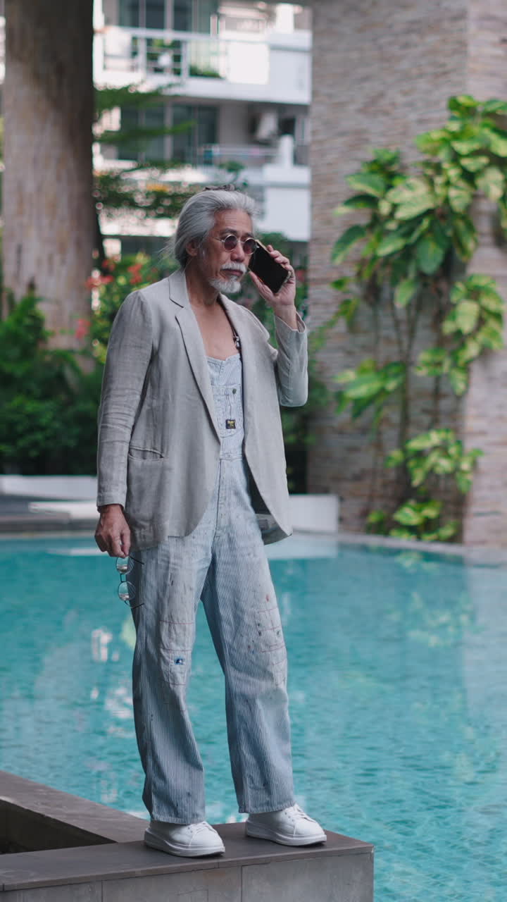 Elegante anziano che parla al telefono a bordo piscina