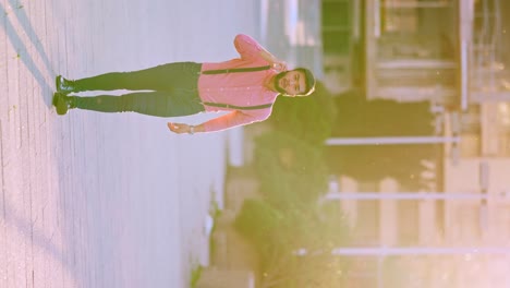 a man in a pink shirt and suspenders posing outdoors during golden hour