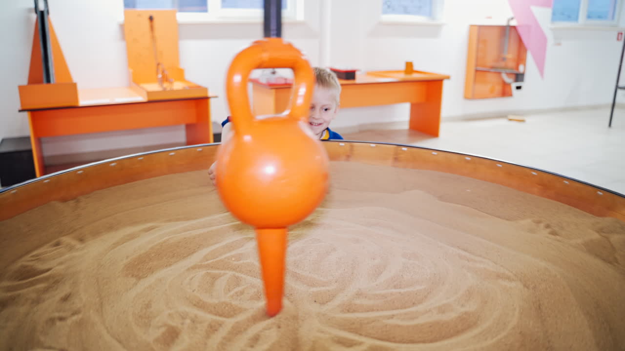 Demonstrasi gerak abadi pendulum. Dua anak kecil melakukan eksperimen praktis di pusat sains. Museum sains.