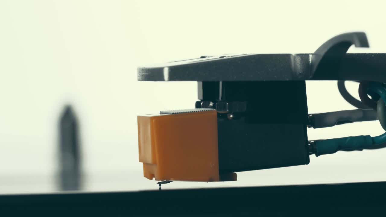 바늘을 가진 스타일러스는 부드럽게 내려와 회전하는 검은 비닐 레코드 (macro) 로 올라갑니다.