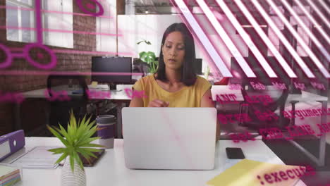 Animation-of-graphs,-globe,-computer-language,-thoughtful-biracial-woman-working-on-laptop-in-office