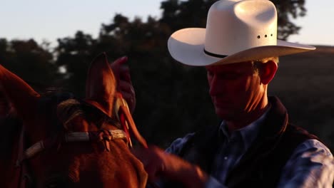 cowboy tightening things up on his horses reigns before he goes for his ride