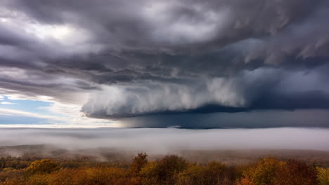 dramatic storm clouds over autumn forest with fog