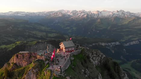 early morning drone view to swiss mountain top with mountain restaurant and first guests