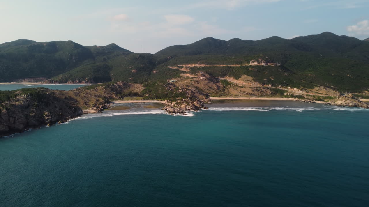 hermoso mar azul claro que termina suavemente en las hermosas playas de arena de la bahía de vinh hy en vietnam con las altas montañas verdes en el fondo