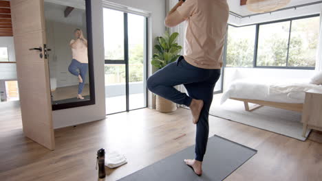 senior biracial man practicing yoga meditation at home