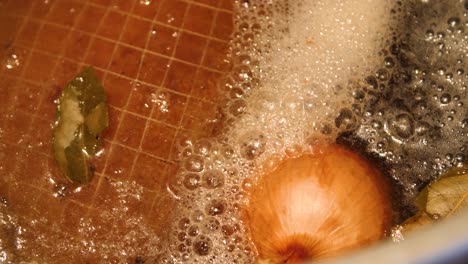 boil-in-the-bag ham boiling in water with bay leaf and yellow onion in a cooking pot for easter