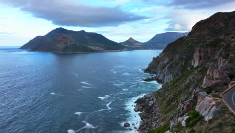 Chapman-Peak-Südafrika-Sonnenuntergang-Fahrt-Luftbild-Drohne-Hout-Bay-Marina-Kapstadt-Fish-Hoek-Gute-Hoffnung-Simon&#39;s-Town-Wellen-Krachen-Zerklüftete-Küste-Aqua-Tiefblaues-Wasser-üppiges-Grün-Sommer-Aufwärtsbewegung