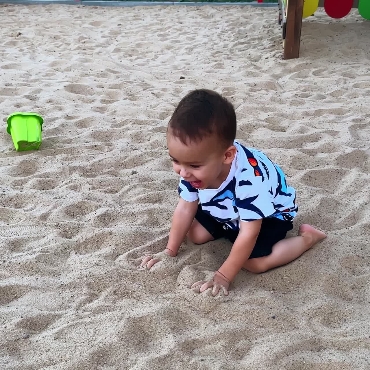 Un bambino felice e gioioso gattona sulla sabbia bianca nel parco giochi. Un bambino adorabile si diverte a passeggiare d'estate