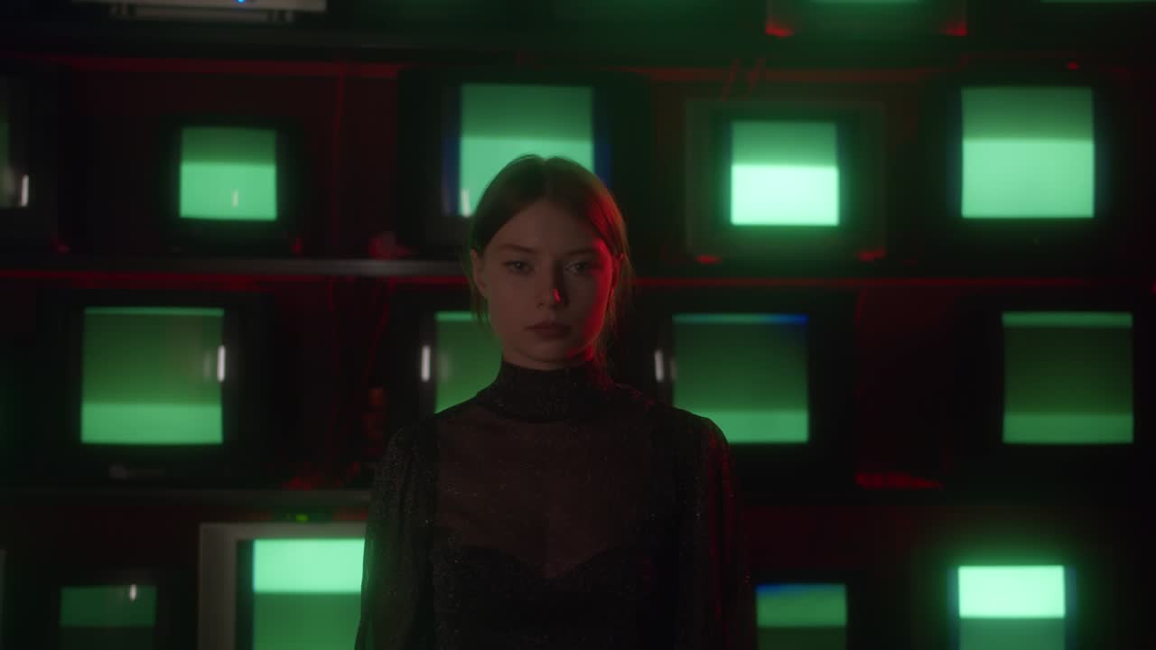 joven mirando a la cámara contra el fondo de viejos televisores con estática y una pantalla verde