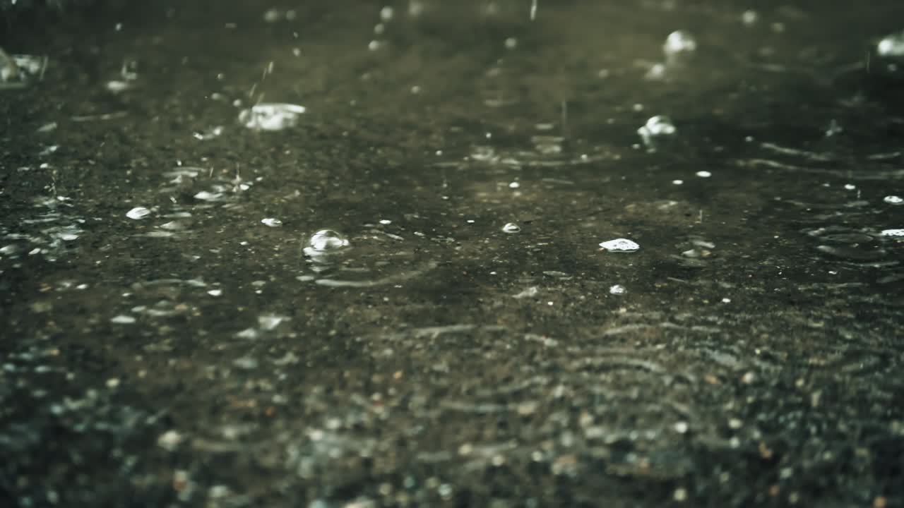 Raindrops splashing on the ground, beautiful rain background, rain puddle. Splash of water.