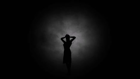 A-modern-youth-dance-performed-by-a-graceful-and-sexy-female-silhouette,-in-the-smoke-against-the-backdrop-of-spotlights