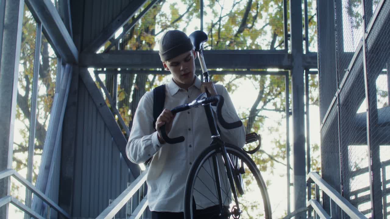 고정 기어 자전거를 들고 금속 계단을 올라가는 젊은 남자