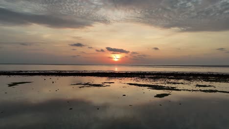 Faszinierende-Drohnenaufnahmen-Eines-Atemberaubenden-Sonnenuntergangs-über-Dem-Meer-Mit-Faszinierenden-Spiegelungen,-Die-Auf-Der-Wasseroberfläche-Tanzen