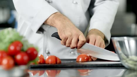 Chef-male-cutting-tomato-at-restaurant-kitchen.-Closeup-chef-cooking-fresh-food.