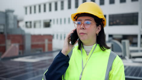 female engineer on solar panel roof talking on phone