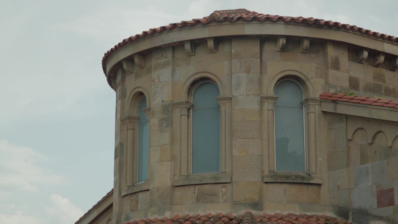 Abside de pedra arredondada e janelas em arco da igreja Iglesia San Pedro perto da Praia de San Lorenzo, Gijón.