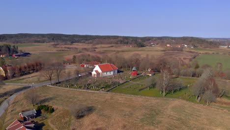 Antena---Iglesia-Y-Cementerio-En-El-Campo,-Bergum,-Suecia,-Plano-General-Hacia-Atrás