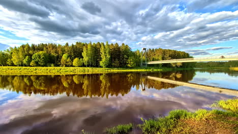 scenic mirrored reflection in gauja river of vanšu tilts bridge and lush valmiera woodland latvia