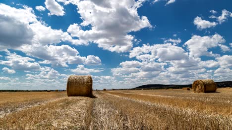 field with bales of hay and beautiful sky time lapse