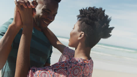 Feliz-Pareja-Afroamericana-Bailando-Y-Tomándose-De-La-Mano-En-La-Playa-Soleada