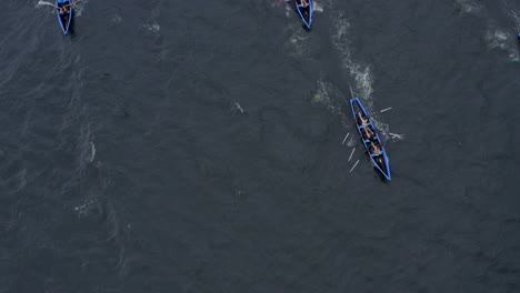 Top-down-aerial-perspective-of-currach-boats-crossing-open-ocean-water-rowing