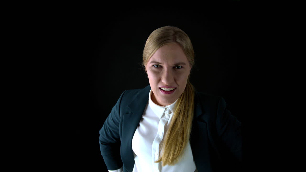 An angry business woman screams into the camera as if to an employee