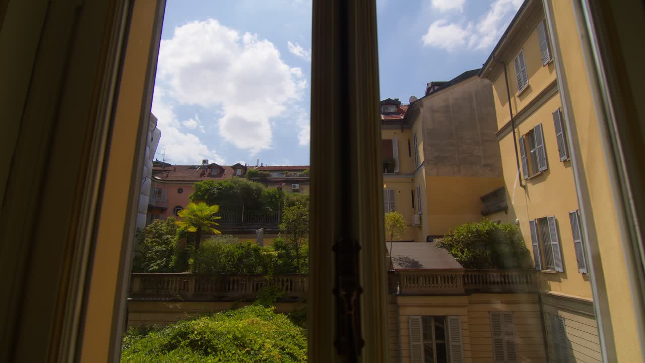 Orbiting right camera shot showing interior of classic Milan building framed through apartment window, capturing historic details in Milan, Italy