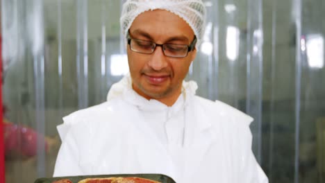 butcher holding a tray of raw meat