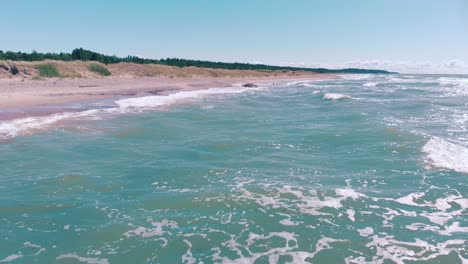 aerial flying over waves crashing onto a pink tropical beach with no people