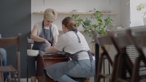 Caucasian-girl-teaches-an-elderly-puppy-to-work-on-a-potter's-wheel.-Assistance-in-the-rehabilitation-and-adaptation-of-pensioners.-Time-lapse-filming-of-an-elderly-woman's-potter's-wheel