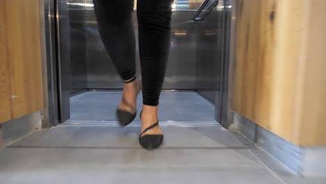 Confident-businesswoman-walks-out-of-elevator-into-modern-office,-foot-close-up