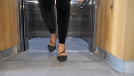 confident businesswoman walks out of elevator into modern office, foot close up