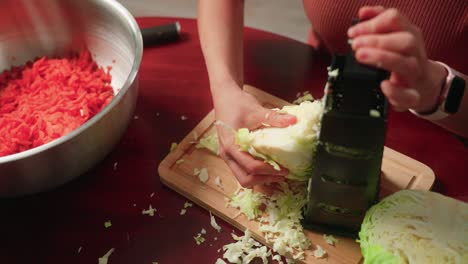 mujer triturando repollo a mano con un rastrillo de queso