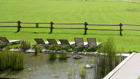 Piscina-De-Estanque-Natural-Con-Césped,-Lirios-Y-Tumbonas-En-Prado-Verde,-Eco,-Concepto-De-Turismo-Ecológico,-Nadie