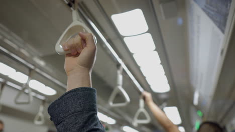 person holding onto a handrail in a subway