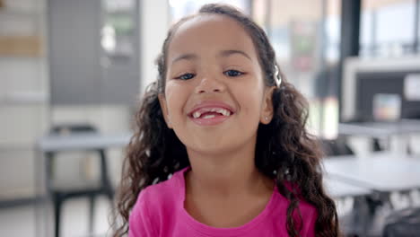 in school, smiling child with missing teeth in classroom, looking at camera