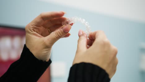 Close-up-shot-of-woman-examining-teeth-straightening-aligners-at-the-dentist