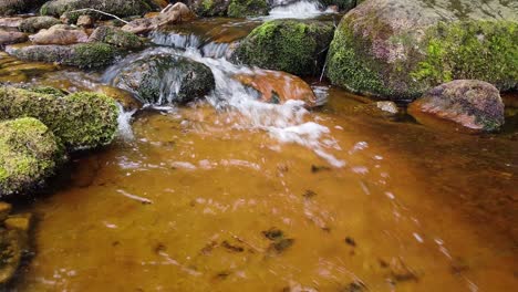 Slow-moving-peaceful-rural-Derbyshire-stream-with-water-flowing-over-small-and-large-rocks