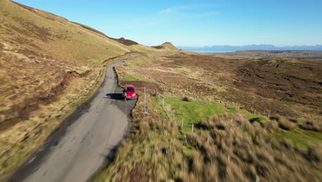 volando a lo largo de scottish highland road con un auto que pasa y un automovilista estacionado en la isla de skye