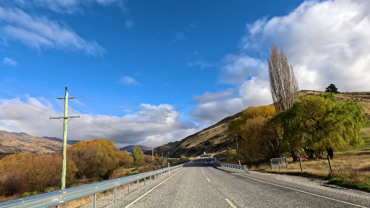A drive through Wanaka, New Zealand, showcasing autumn foliage, clear skies, and mountainous terrain. Captured with smooth camera movement and natural lighting